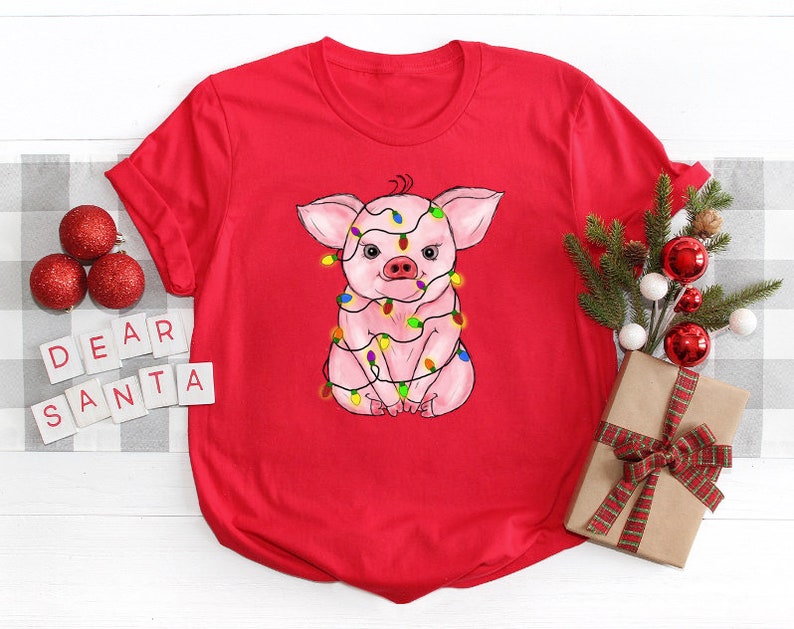 May include: Red t-shirt with a pink pig wearing Christmas lights. The text "Dear Santa" is on a white background.