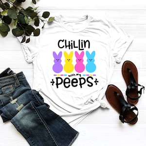 May include: White t-shirt with the text "Chillin with my peeps" and three colorful marshmallow peeps.
