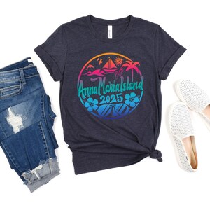 Puede incluir: Una camiseta azul oscuro con un dise&ntilde;o gr&aacute;fico colorido que presenta una palmera, un velero y el texto "Anna Maria Island 2025".