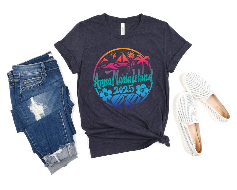 Puede incluir: Una camiseta azul oscuro con un dise&ntilde;o gr&aacute;fico colorido que presenta una palmera, un velero y el texto "Anna Maria Island 2025".