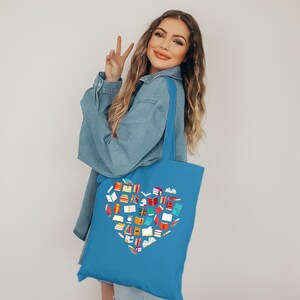 May include: A blue tote bag with a heart-shaped design made of colorful book illustrations. The bag is made of canvas and has a long handle.