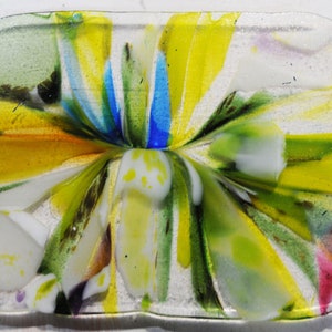 Op de afbeelding: Een kleurrijk glazen schaaltje met een witte achtergrond en gele, groene, blauwe en roze accenten. Het glas is getextureerd en heeft een uniek, abstract ontwerp.