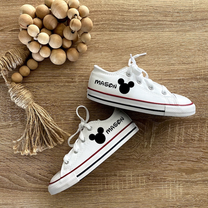 Może przedstawiać: Białe buty z pł&oacute;tna z czarnymi uszami Myszki Miki i nadrukiem "MASON" na każdym bucie.