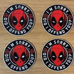 May include: Four round patches featuring the Deadpool character's face in red and black. Each patch has the text "I'M SORRY, DID I OFFEND YOU?" in a circular pattern around the image.