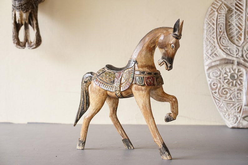 May include: A wooden horse figurine with intricate carvings and colorful paint details. The horse is standing on its hind legs with its head lowered.