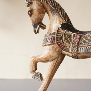 May include: A wooden horse figurine with intricate carvings and colorful paint details. The horse is in a rearing pose with its head turned to the side.