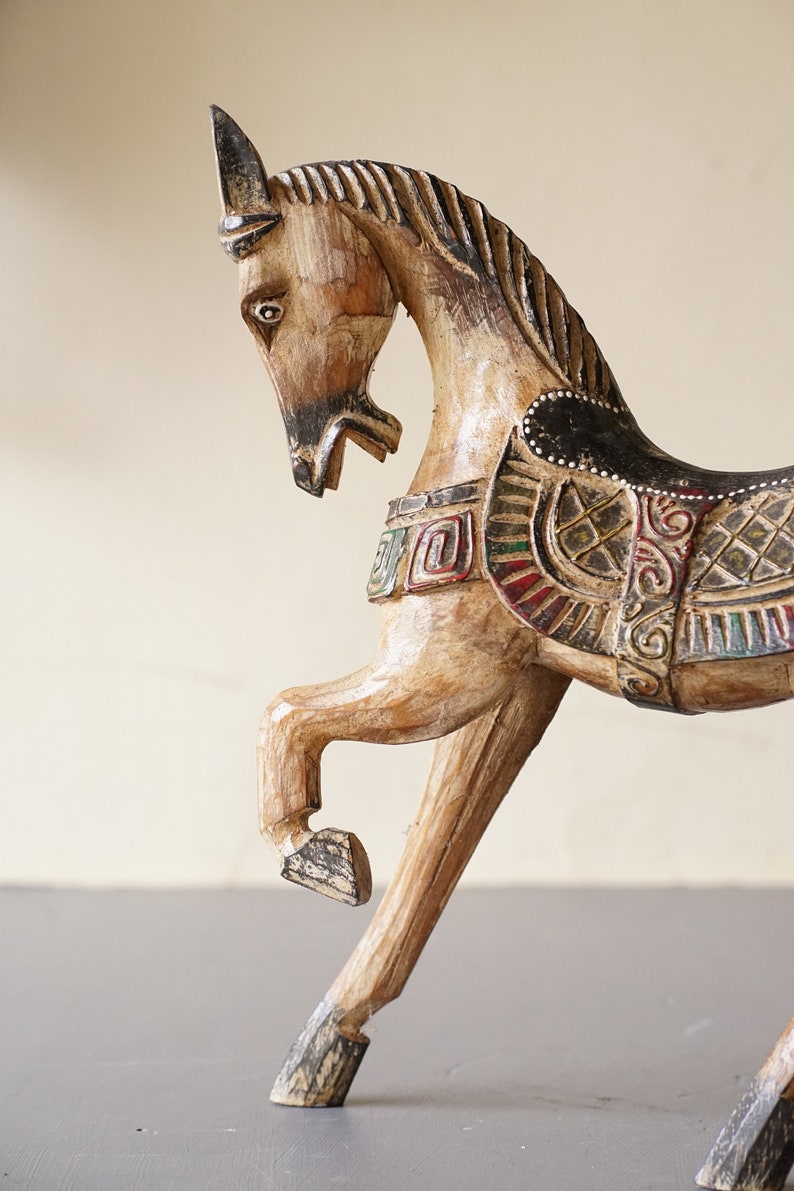 May include: A wooden horse figurine with intricate carvings and colorful paint details. The horse is in a rearing pose with its head turned to the side.