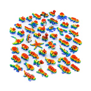 Puede incluir: Una colección de figuritas de animales coloridas pintadas a mano. Las figuritas están hechas de arcilla polimérica y presentan un esquema de color arcoíris. Los animales incluyen un pingüino, una estrella de mar, una tortuga, un escorpión, una mariquita, un gecko, una serpiente, una mariposa y más.