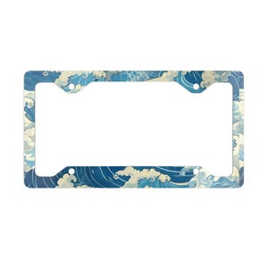 May include: A rectangular license plate frame featuring a repeating graphic pattern of stylized blue ocean waves with white foam crests. The frame has four circular mounting holes, one in each corner, and a wide border design throughout the piece.