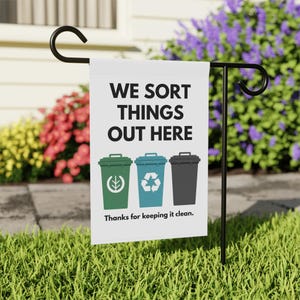 May include: A white garden flag with the text "WE SORT THINGS OUT HERE" and three bins in green, blue, and grey. The green bin has a leaf symbol, the blue bin a recycling symbol. The text "Thanks for keeping it clean" is below.