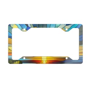 May include: A colorful license plate frame with a stained glass design of a sunset over water. The frame is made of metal and has four holes for mounting.