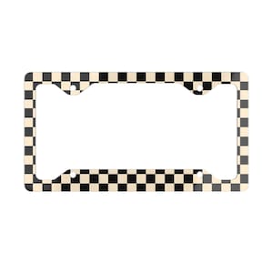 May include: Black and white checkered license plate frame. The frame is made of metal and has a glossy finish.