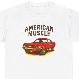 Peut inclure: T-shirt blanc avec un dessin d'une voiture de sport américaine rouge. Les mots "AMERICAN MUSCLE" sont imprimés au-dessus de la voiture dans une police marron vintage. L'illustration de la voiture est détaillée.