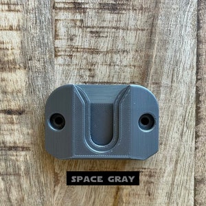 May include: A gray plastic wall mount with a U-shaped cutout. The text "SPACE GRAY" is printed below the mount.