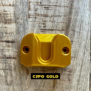 May include: A gold-colored plastic wall mount with two screw holes. The text "C3PO GOLD" is printed below the mount.