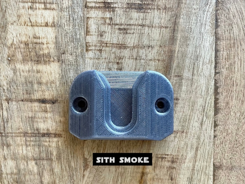 May include: A gray plastic wall mount with two screw holes and a U-shaped cutout. The text "SITH SMOKE" is printed below the mount.