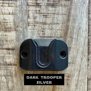 May include: A dark gray wall mount hook with a U-shaped opening. The hook is labeled "DARK TROOPER SILVER".