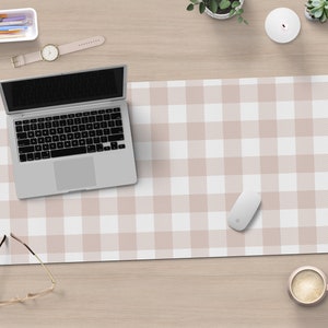 May include: A white and light pink checkered desk mat with a laptop, a mouse, and glasses on top.