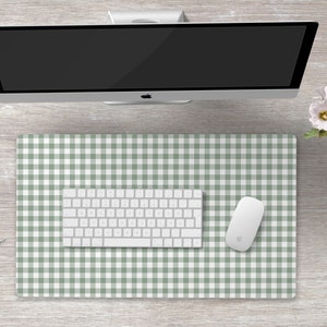 Pode incluir: Um tapete de mesa xadrez verde e branco com um teclado e um rato brancos em cima. O tapete de mesa est&aacute; sobre uma superf&iacute;cie de madeira clara.