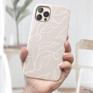 May include: A beige phone case with a white abstract leaf pattern. The case has a camera lens cutout in the upper left corner.
