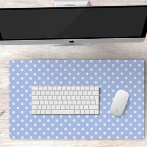 Pode incluir: Um tapete de mesa azul e branco de bolinhas com um teclado branco e um rato branco em cima.