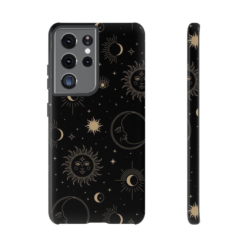 May include: A black phone case with a gold celestial pattern featuring suns, moons, and stars. The case has a cutout for the camera lens.