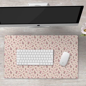 K&ouml;nnte beinhalten: Eine wei&szlig;e Schreibtischunterlage mit einem rosa Blumenmuster. Auf der Unterlage liegen eine wei&szlig;e Tastatur und eine wei&szlig;e Maus.