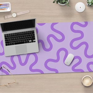 May include: A purple desk mat with a wavy pattern. A laptop, mouse, and glasses are on the mat.