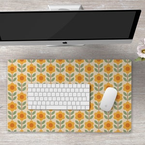 May include: A white computer keyboard and mouse on a desk mat with a retro floral pattern featuring yellow and orange flowers on a beige background.