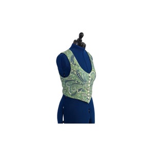 Può includere: Un gilet verde e blu con motivo paisley e chiusura con bottoni.