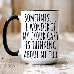 May include: White ceramic coffee mug with a black handle and black rim. The mug has a funny saying printed on it: "Sometimes... I wonder if my [your car] is thinking about me too."
