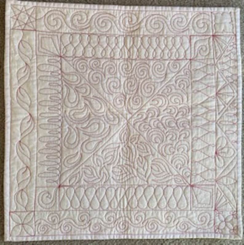 May include: A white quilted fabric with a variety of red stitching patterns, including swirls, waves, and geometric shapes.