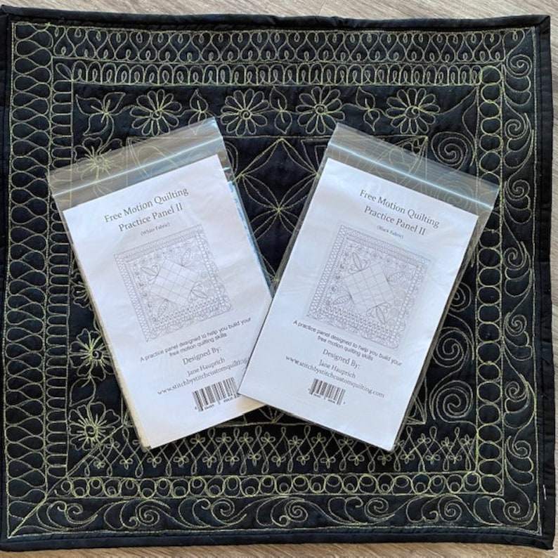 May include: Two white envelopes with black text and a black and white line drawing of a quilt block. The text on the envelopes reads "Free Motion Quilting Practice Panel II" and "Designed By: Jane Hauprich".
