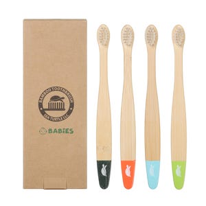May include: A set of four bamboo toothbrushes with light-colored bristles and natural wood handles. Each handle has a colored base: black, orange, blue, and green. A cardboard box with the text "BABIES" and a logo is on the left.