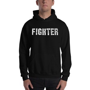May include: Black hooded sweatshirt with the word "FIGHTER" printed in white on the front.