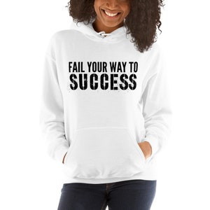 May include: White hooded sweatshirt with the text "Fail your way to success" printed in black with a distressed effect.