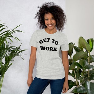 May include: A heather grey t-shirt with black text that reads "GET TO WORK" in an arched font.