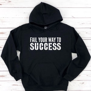 May include: Black hooded sweatshirt with the text "Fail your way to success" in white lettering with a distressed effect.
