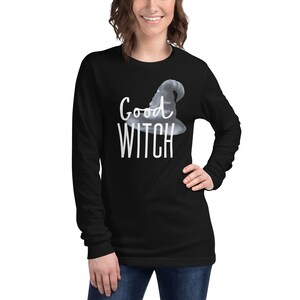 May include: Black long-sleeve shirt with a white graphic of a witch's hat and the text "Good Witch".