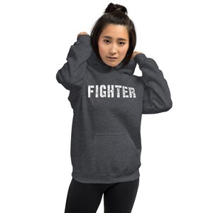 May include: A dark gray hooded sweatshirt with the word "FIGHTER" printed in white on the front.