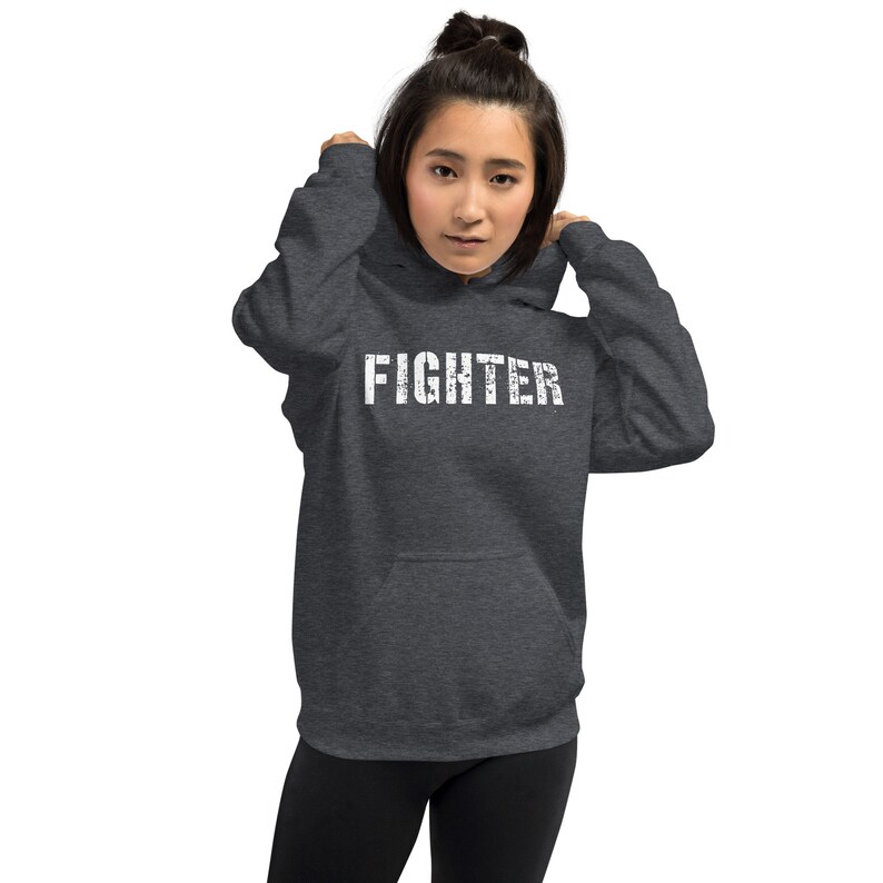May include: A dark gray hooded sweatshirt with the word "FIGHTER" printed in white on the front.