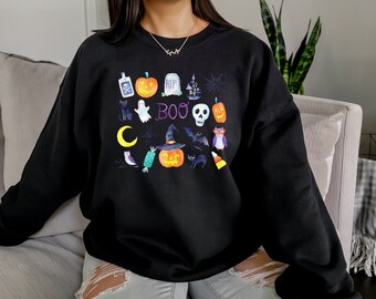 Könnte beinhalten: Schwarzes Sweatshirt mit einem Halloween-Motiv mit verschiedenen gruseligen Symbolen, darunter Kürbisse, Geister, Fledermäuse, ein Schädel, ein Hexenhut und das Wort "BOO".