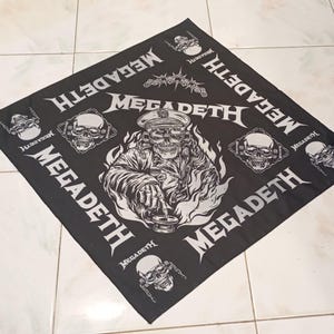 May include: Black square bandana featuring a detailed white illustration of a skull in a military cap, holding a mortar and pestle, surrounded by flames. The word "MEGADETH" is printed in white around the edges, along with skull graphics.