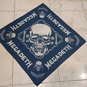 May include: A navy blue bandana featuring a white skull graphic with goggles and the word "MEGADETH" in a stylized font. Additional skull and chain graphics are also present.