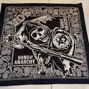 May include: Black bandana featuring a white graphic of a grim reaper holding a rifle, with the text "SONS OF ANARCHY". The border has a paisley and skull design.