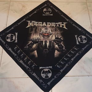May include: Black square bandana featuring the band name "MEGADETH" in silver lettering. The center graphic depicts a cyborg figure holding a sword. The border includes the band's name and skull imagery.