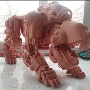 Könnte beinhalten: Ein 3D-gedrucktes Modell eines Robotertiers, das einem großen Katzen- oder Hundeartigen ähnelt. Das Modell ist aus hellbraunem Kunststoff gefertigt und hat ein detailliertes, mechanisches Design. Das Modell ist in einer hockenden Position dargestellt, mit gesenktem Kopf und entblößten Zähnen.