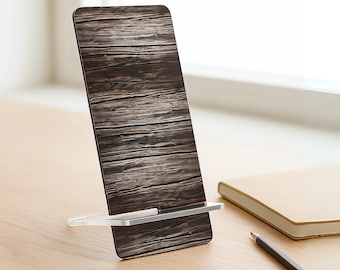 May include: A wooden-textured phone stand with a clear acrylic base. The phone stand is angled, displaying a brown and gray wood grain pattern. A notebook and pencil are in the background.