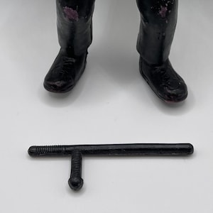 May include: A black plastic police baton with a textured handle.