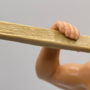 May include: A brown wooden board with a rough texture. The board is held by a hand.